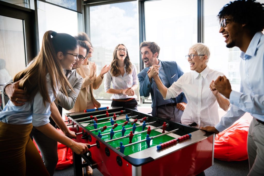 change company culture Colleagues playing table football in the break in office